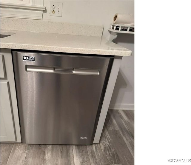 room details featuring baseboards, light stone countertops, wood finished floors, and stainless steel dishwasher