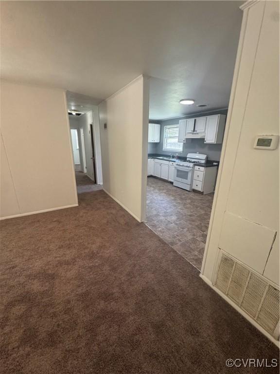interior space featuring dark colored carpet, a sink, baseboards, and visible vents