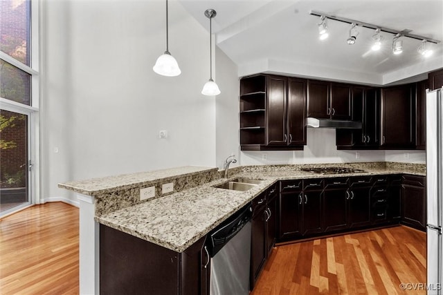 kitchen featuring light wood finished floors, stainless steel appliances, open shelves, a sink, and a peninsula