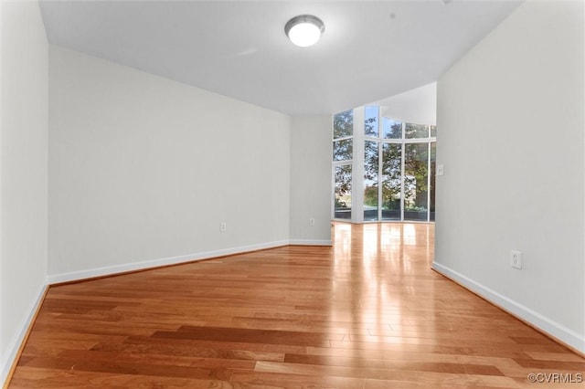unfurnished room featuring baseboards, wood finished floors, and floor to ceiling windows