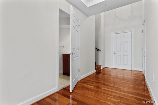 hallway featuring stairway, baseboards, and light wood-style floors