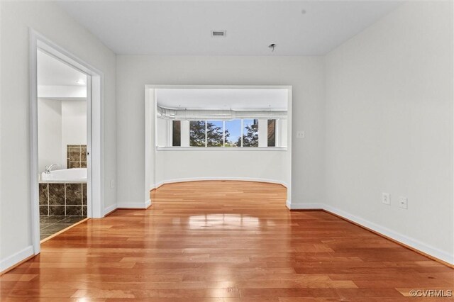 spare room with baseboards, visible vents, and hardwood / wood-style flooring