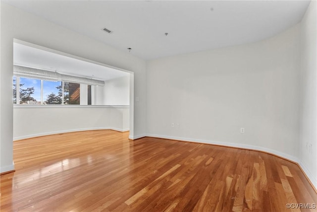 empty room featuring visible vents, baseboards, and wood finished floors
