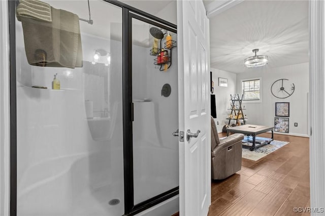 bathroom with wood finished floors, baseboards, and a stall shower