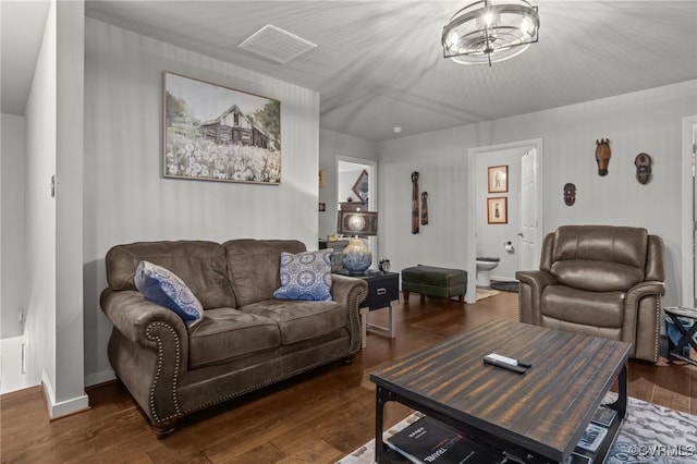 living area featuring visible vents, wood finished floors, and an inviting chandelier