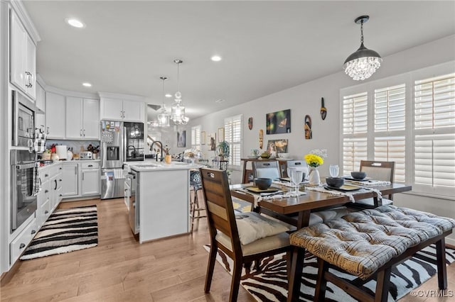 dining space featuring recessed lighting, light wood-style floors, and a notable chandelier