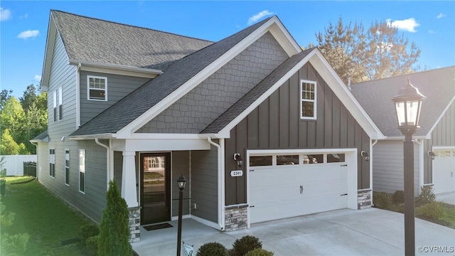 craftsman inspired home featuring board and batten siding, roof with shingles, driveway, and stone siding