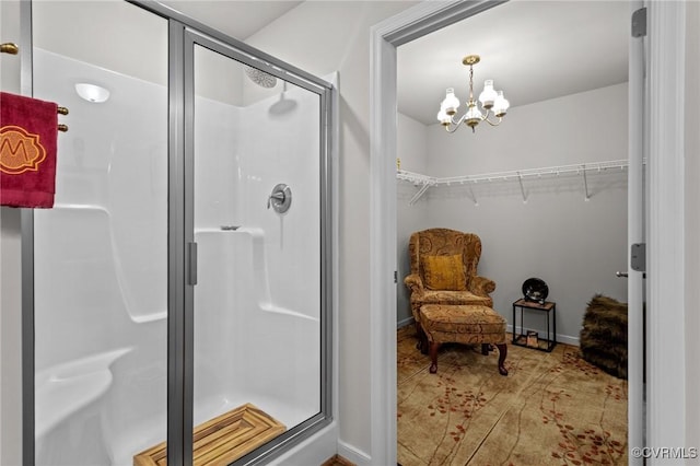 full bath with baseboards, a notable chandelier, a shower stall, and a spacious closet