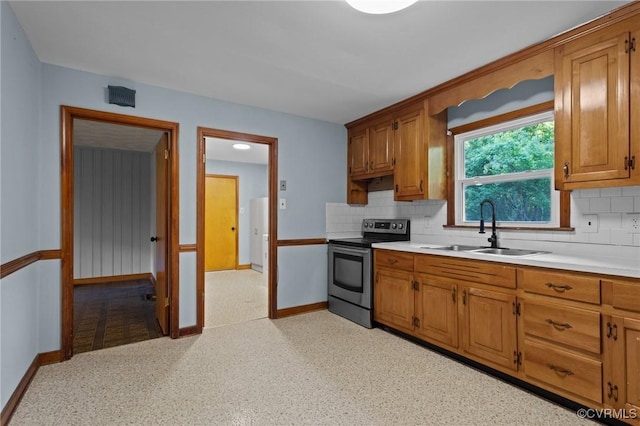 kitchen with baseboards, a sink, stainless steel electric range, and tasteful backsplash
