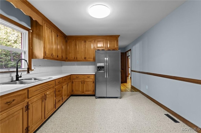 kitchen with stainless steel refrigerator with ice dispenser, a sink, visible vents, and light countertops