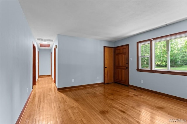 unfurnished room featuring baseboards, visible vents, attic access, and light wood-type flooring
