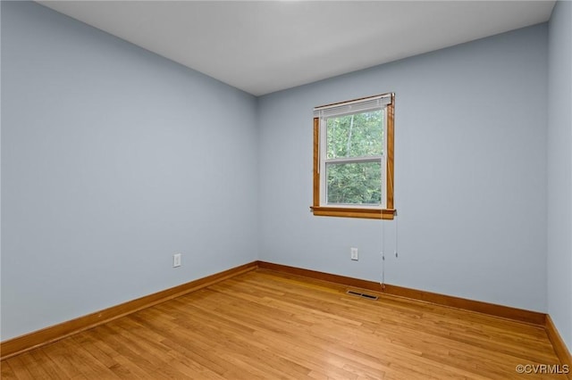 empty room featuring baseboards, light wood-type flooring, and visible vents