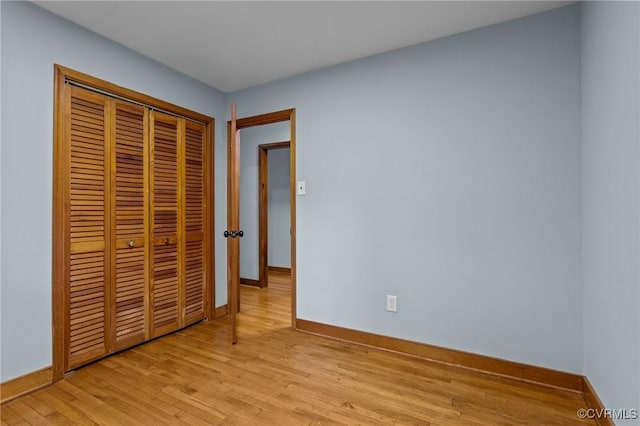 unfurnished bedroom with baseboards, a closet, and light wood-type flooring