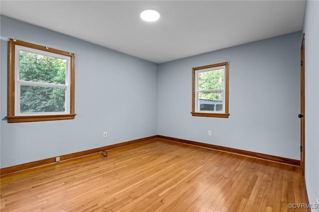 unfurnished room featuring baseboards, visible vents, and light wood finished floors