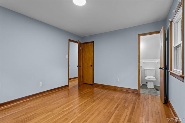 unfurnished bedroom featuring baseboards, light wood-style flooring, and ensuite bath