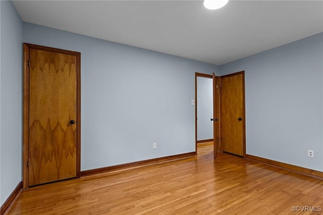 empty room with baseboards and light wood finished floors