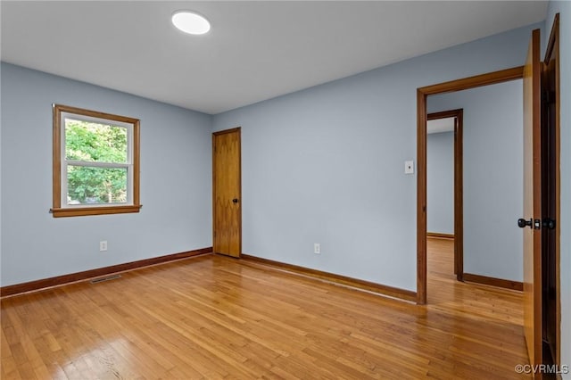 spare room with baseboards, light wood finished floors, and visible vents