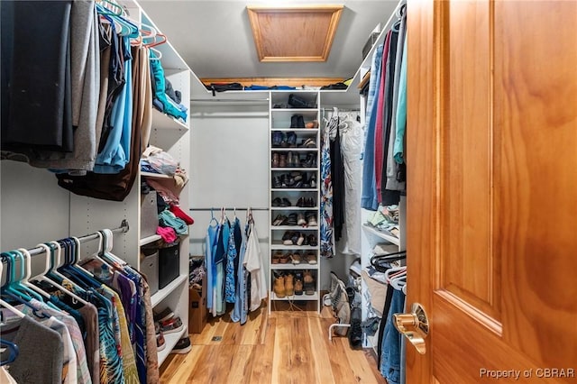 walk in closet with attic access and wood finished floors