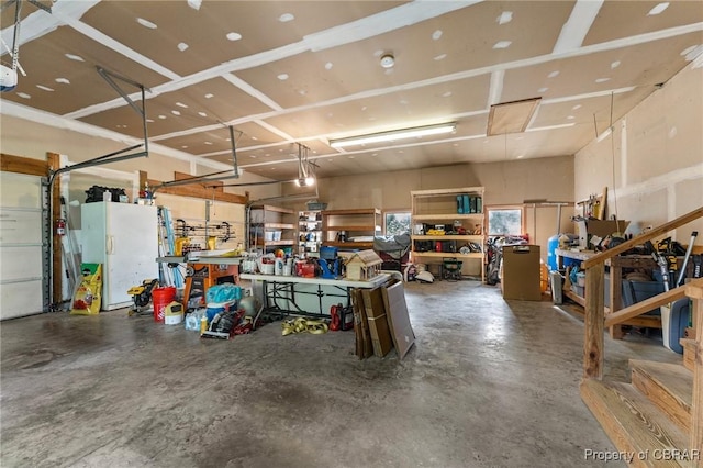 garage featuring a workshop area and freestanding refrigerator