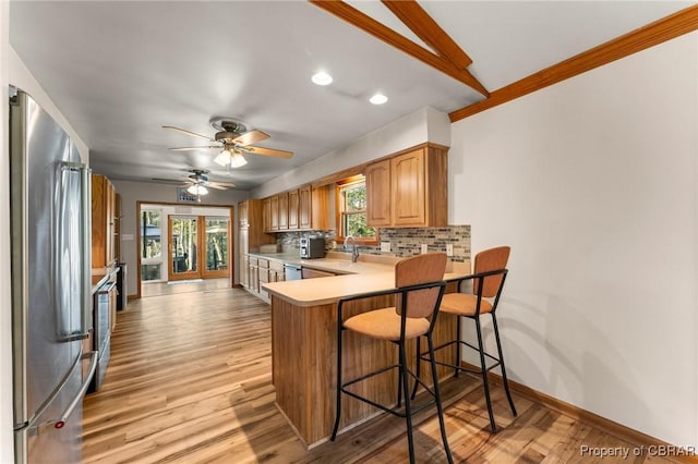 kitchen with stainless steel appliances, a kitchen breakfast bar, recessed lighting, backsplash, and light countertops