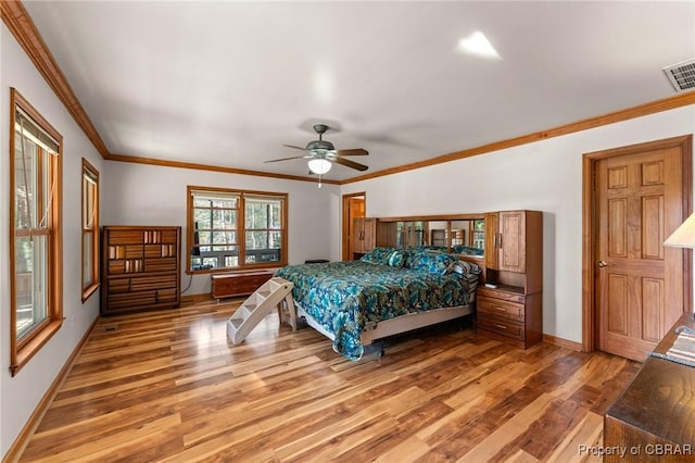 bedroom with crown molding, light wood-type flooring, ceiling fan, baseboards, and visible vents