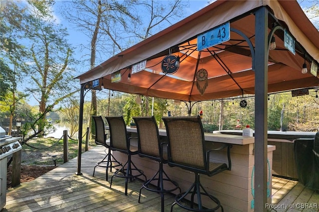 wooden terrace featuring outdoor dry bar, a gazebo, and a water view