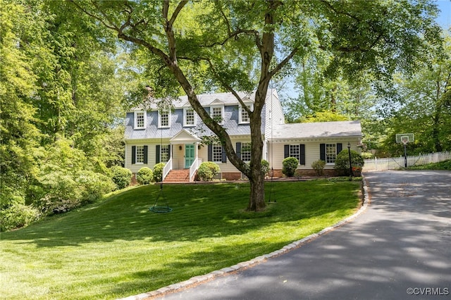 view of front of house with fence, aphalt driveway, and a front yard