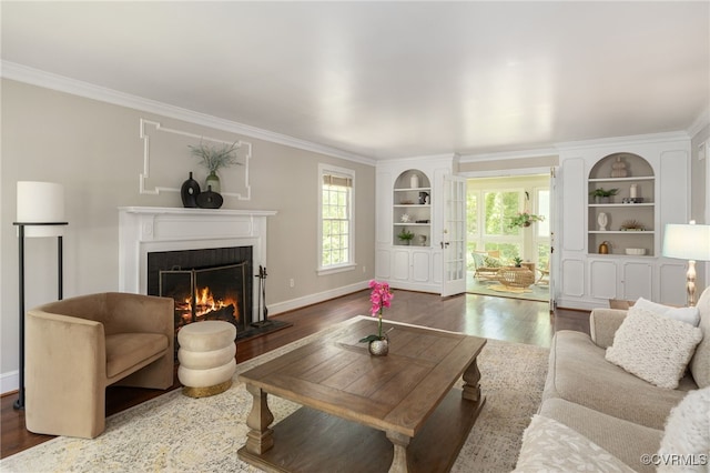 living room featuring crown molding, a warm lit fireplace, plenty of natural light, and wood finished floors