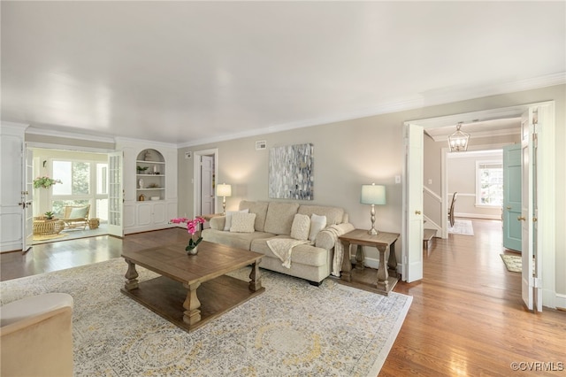 living room with visible vents, ornamental molding, stairs, baseboards, and light wood-style flooring