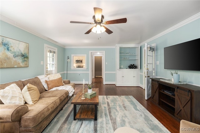 living area featuring crown molding, baseboards, dark wood-type flooring, and ceiling fan