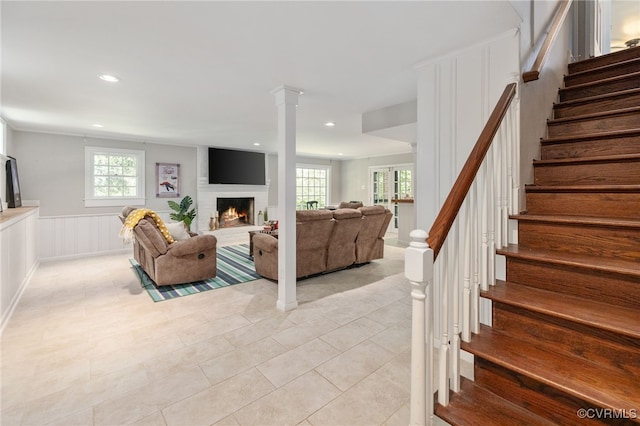 living area with stairs, light tile patterned floors, a wealth of natural light, and a fireplace