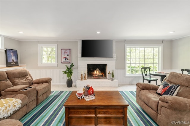 living room with crown molding, recessed lighting, a wainscoted wall, and a fireplace