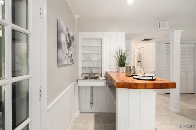 interior space featuring light tile patterned floors, visible vents, wainscoting, and a sink
