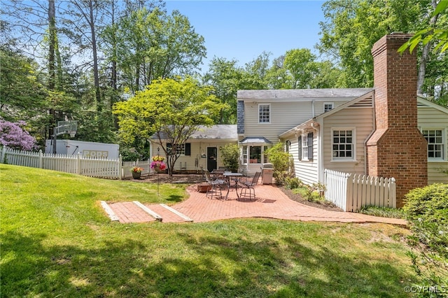 back of house with a lawn, a patio, fence, and a chimney