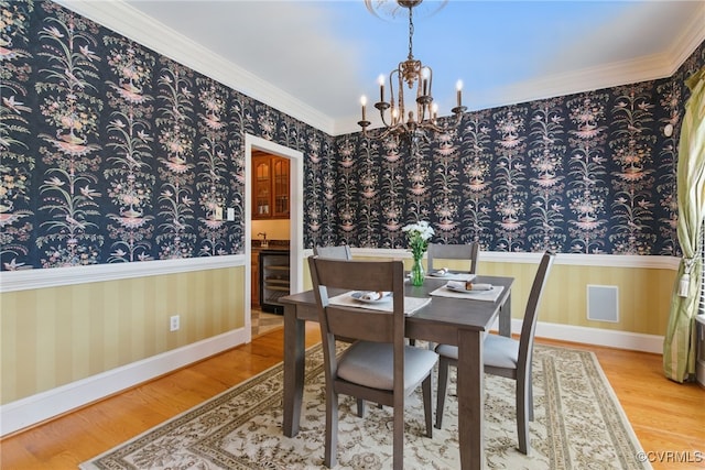 dining space featuring wallpapered walls, wine cooler, wood finished floors, and a chandelier