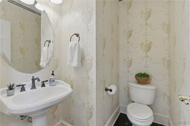 bathroom featuring baseboards, a sink, and toilet