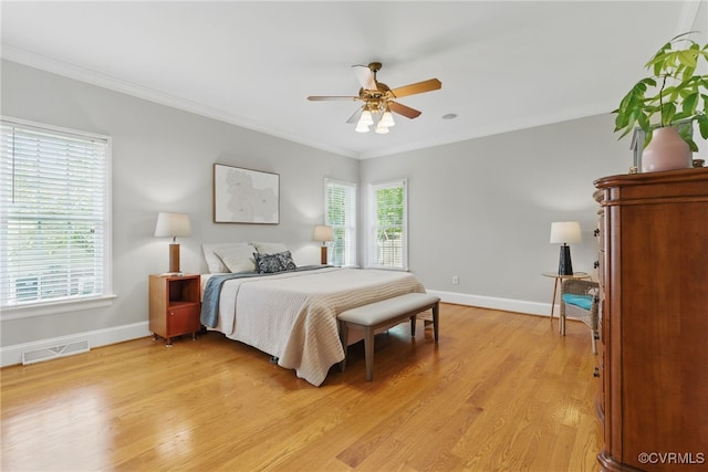 bedroom featuring visible vents, a ceiling fan, ornamental molding, light wood-type flooring, and baseboards