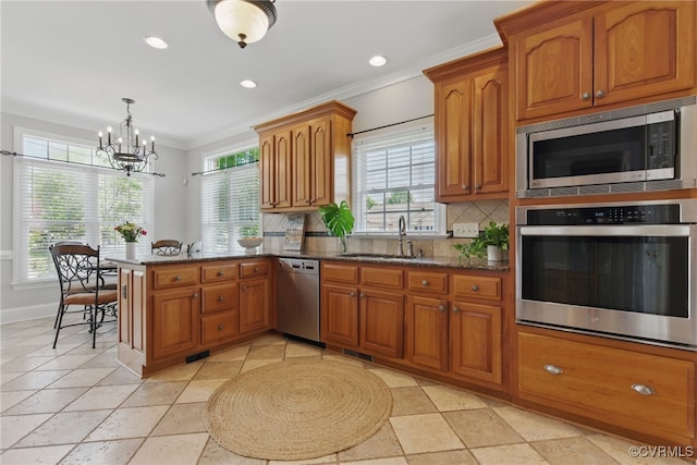 kitchen featuring brown cabinets, a notable chandelier, stainless steel appliances, and a sink