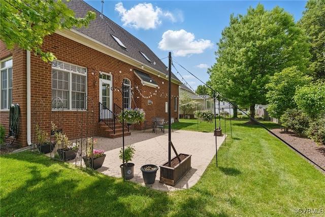 exterior space featuring a lawn, brick siding, roof with shingles, and a patio