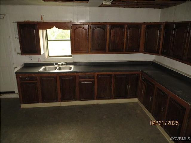 kitchen featuring dark countertops, dark brown cabinets, and a sink