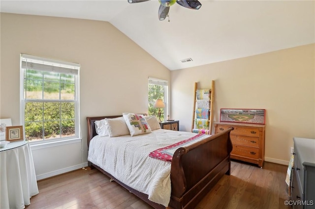 bedroom featuring baseboards, visible vents, wood finished floors, and lofted ceiling