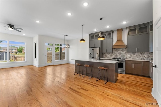 810 N 32nd St, Richmond, VA 23223 - kitchen with custom exhaust hood, high quality appliances, a breakfast bar area, open floor plan, and light wood-style flooring