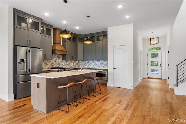 810 N 32nd St, Richmond, VA 23223 - kitchen with stainless steel appliances, custom range hood, a sink, backsplash, and light wood-style floors
