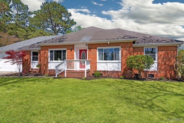 ranch-style house featuring an attached garage, brick siding, a front yard, and roof with shingles