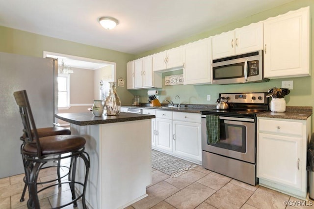 kitchen featuring white cabinets, stainless steel appliances, a kitchen island, and a kitchen bar
