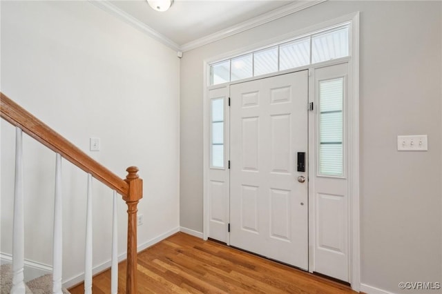 entryway with baseboards, light wood-style floors, stairs, and crown molding