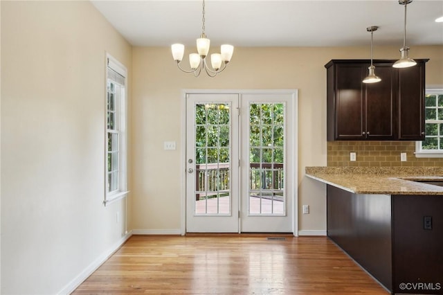 doorway featuring baseboards, an inviting chandelier, and light wood-style flooring
