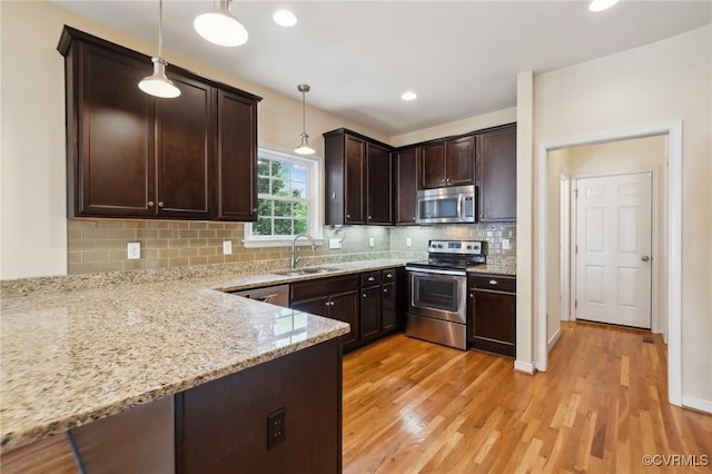 kitchen with light wood-style floors, dark brown cabinetry, stainless steel appliances, and a sink