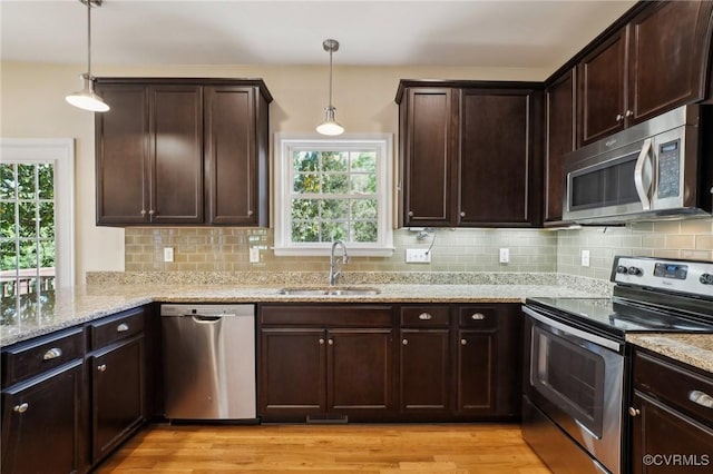 kitchen with light stone countertops, a wealth of natural light, appliances with stainless steel finishes, and a sink