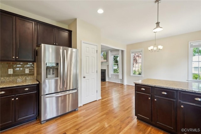 kitchen with dark brown cabinets, hanging light fixtures, an inviting chandelier, light wood-style flooring, and stainless steel refrigerator with ice dispenser